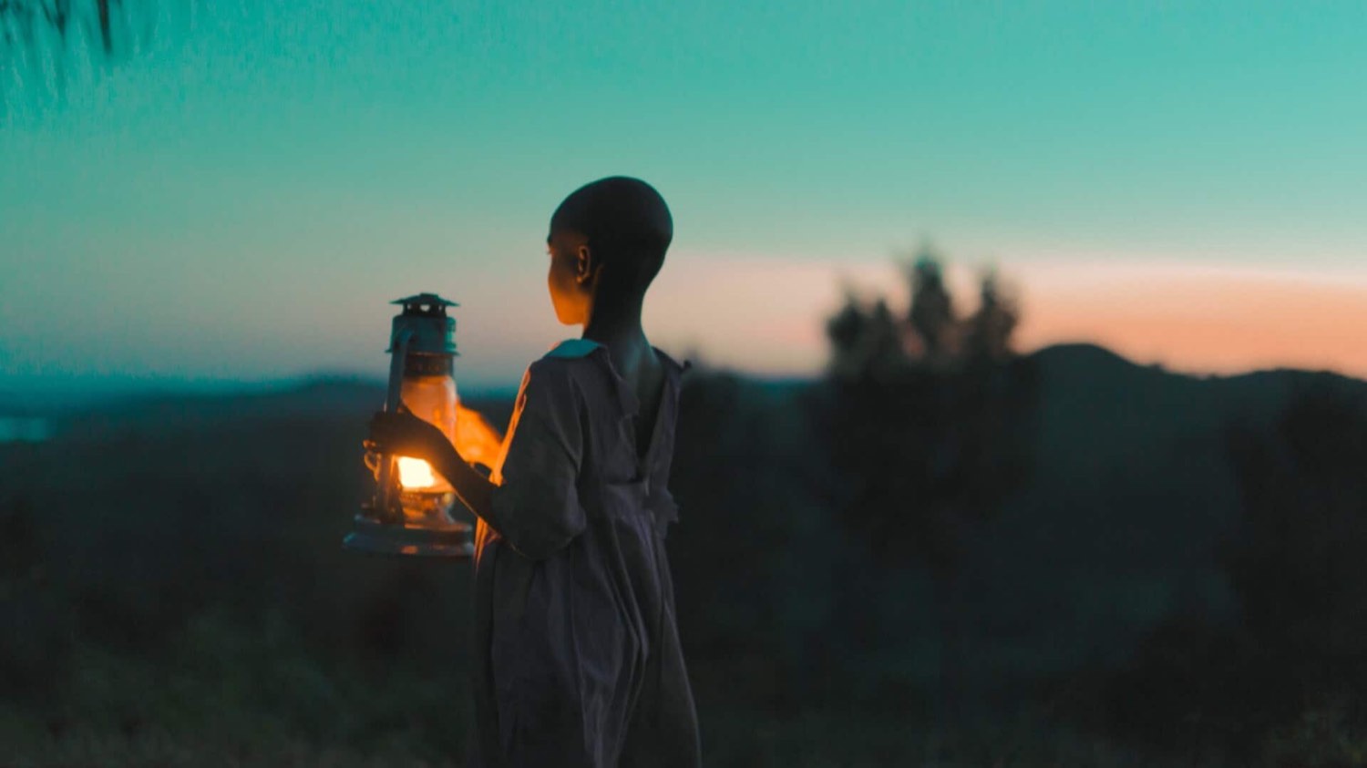 A child carrying a lantern at dusk